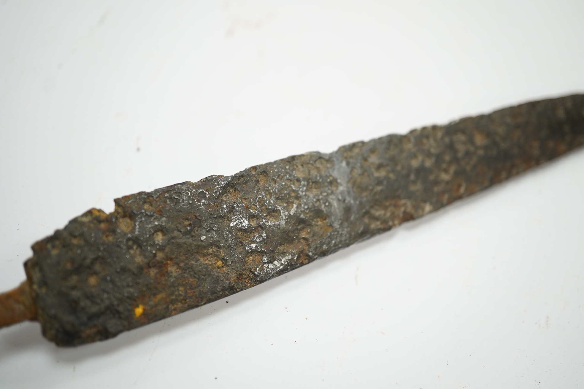 A 15th or 16th century dagger in excavated condition, broad tapered single edge blade, bronze crosspiece with side ring and fluted pommel cap, grip now missing. Condition - poor